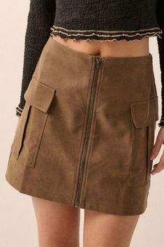 Faux leather mini skirt. Full front zipper closure. Flap cargo pockets. Thigh length. A-line silhouette. Relaxed fit. 55% Cotton, 45% PU. Imported. Designed in LA. Model wears size S. Fall Fitted Mini Skirt With Side Pockets, Fitted Mini Skirt With Side Pockets For Fall, Mini Skirt With Zipper Closure For Work, Fall Skort With Pockets And Short Length, Fall Mini Skirt With Side Pockets, Fall Mini Skirt With Zipper Closure, Fall Mini Skort With Pockets, Fall Mini Length Skort With Pockets, Utility Mini Cargo Skirt With Pockets For Fall