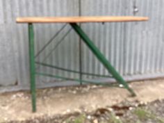 an old wooden table sitting in front of a metal wall