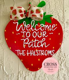 a welcome sign hanging on the side of a white wall with red and green decorations