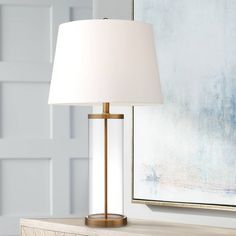 a lamp that is sitting on top of a wooden table in front of a painting