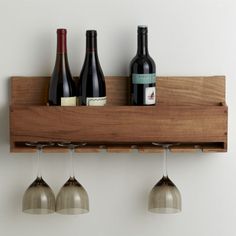 three wine glasses are hanging from a wooden shelf