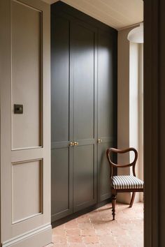 a chair sitting in front of a door with two doors on each side and an armoire next to it