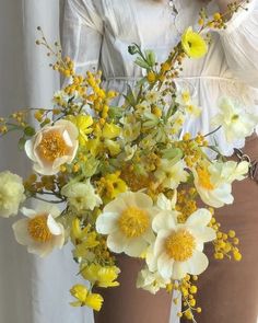 a woman holding a bouquet of yellow and white flowers