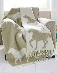 a horse blanket sitting on top of a couch next to a chair in a living room