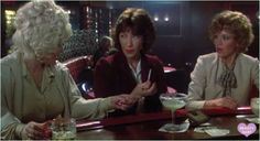 three women sitting at a bar with drinks in front of them and one woman holding her hand out