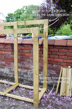 a wooden frame with measurements for the top and bottom posts, in front of a brick wall