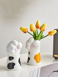 two ceramic vases with yellow flowers in them on a table next to an old radio