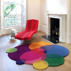 a living room filled with furniture and a colorful rug on top of a hard wood floor