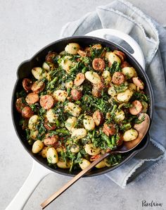 a skillet filled with potatoes, broccoli and sausage