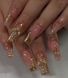 a woman's nails with gold decorations on them and some nail polish in the middle