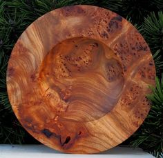 a wooden plate sitting on top of a table next to some pine needles and branches