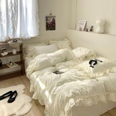 an unmade bed with white sheets and pillows in a room next to a window