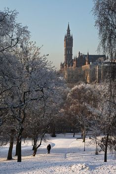 a person walking through the snow in front of a castle