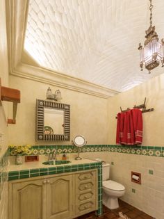 a bathroom with green and white tile on the floor, sink, toilet and mirror