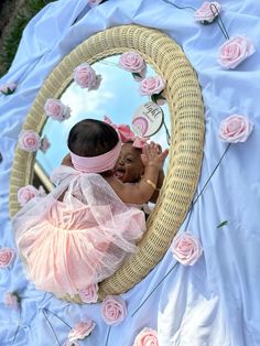 a baby girl in a pink dress is looking into a mirror with roses on it