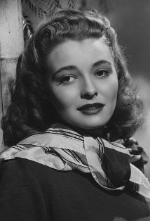 a black and white photo of a woman leaning against a wall with her hand on her shoulder