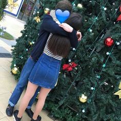 two people hugging in front of a christmas tree