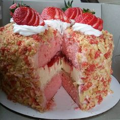 a cake with strawberries and cream on top is cut in half to show the layers