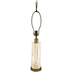 a glass and brass table lamp with a cord attached to the light bulb, on a white background