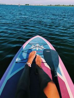 a person sitting on top of a surfboard in the water with their feet propped up