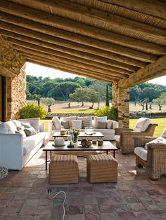 an outdoor living area with wicker furniture and stone flooring is featured in this image