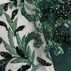 green and white sequins on mesh fabric with floral design, closeup view