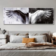 an image of two white and black wings on a wall above a bed with pillows