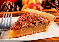 a slice of pecan pie on a napkin with a fork and pine cones in the background