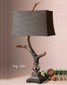 a table lamp with an antler on it and a small animal figurine next to it