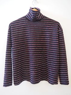 a black and purple striped sweater hanging on a white wall