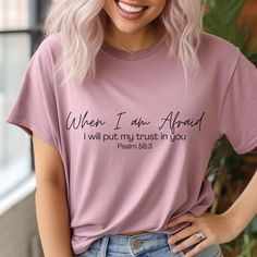 a woman with blonde hair wearing a pink t - shirt that says, when i am afraid, i will put my trust in you