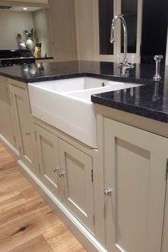 a kitchen with white cabinets, black counter tops and wooden floors is pictured in this image