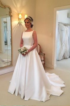 a woman standing in front of a mirror wearing a white dress and holding a bouquet