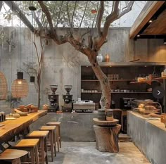 a restaurant with wooden tables and stools next to a large tree in the center