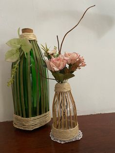 two vases that have flowers in them on a wooden table next to each other