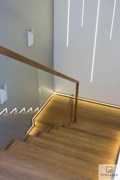 an empty room with wooden flooring and white walls, illuminated by lights on the wall