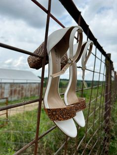 a pair of white high heeled shoes hanging on a fence