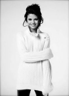 a woman with her arms crossed wearing a white sweater