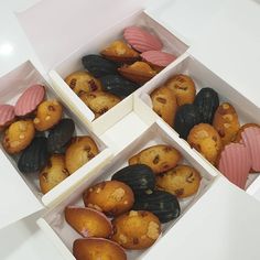 four boxes filled with assorted pastries on top of a white table next to each other