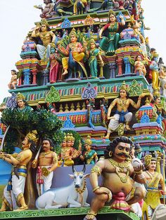 an elaborately decorated hindu temple with statues on the top and below it's roof