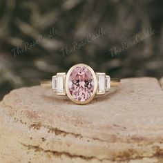 a pink diamond ring sitting on top of a rock