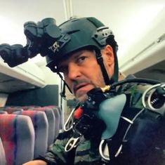 a man wearing a helmet and goggles on his head while sitting in an airplane