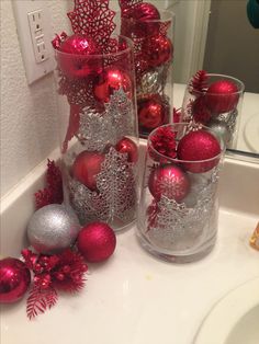 red and silver ornaments in glass vases on bathroom sink