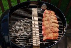 there is a steak on the grill with tongs next to it and another piece of meat being grilled