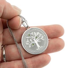 Celebrate the beauty and meaning of the Celtic Tree of Life with this exquisite stainless steel pendant necklace. The intricate Tree of Life design is reverse sandblasted into a substantial 1-inch round pendant, accented with trinity knots and three genuine light emerald stones for a pop of color and Irish flair. The 18-inch chain with 3-inch extender allows you to adjust the length for a perfect fit. The Tree of Life is a powerful symbol in Celtic culture, representing the interconnectedness of Symbolic Silver Jewelry With Laser Engraving, Symbolic Silver Laser Engraved Jewelry, Symbolic Laser Engraved Silver Jewelry, Symbolic Silver Necklace With Laser Engraving, Metal Jewelry With Engraving Option For Gift, Engravable Metal Jewelry As Gift, Nickel Free Stainless Steel Necklace For Anniversary, Nickel-free Stainless Steel Necklace For Anniversary, Laser Engraved Symbolic Round Jewelry