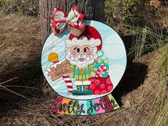 a wooden sign with a santa clause on it next to a tree and grass area