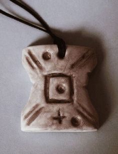 a ceramic ornament hanging from a cord on a blue surface with a cross in the center