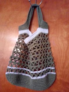 a crocheted bag hanging from a hook on a wooden table with a pair of scissors