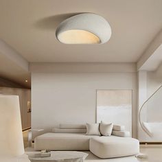 a modern living room with white furniture and large circular light fixture in the ceiling area