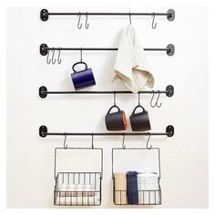 two metal racks holding pots and pans with hooks hanging on the wall next to each other